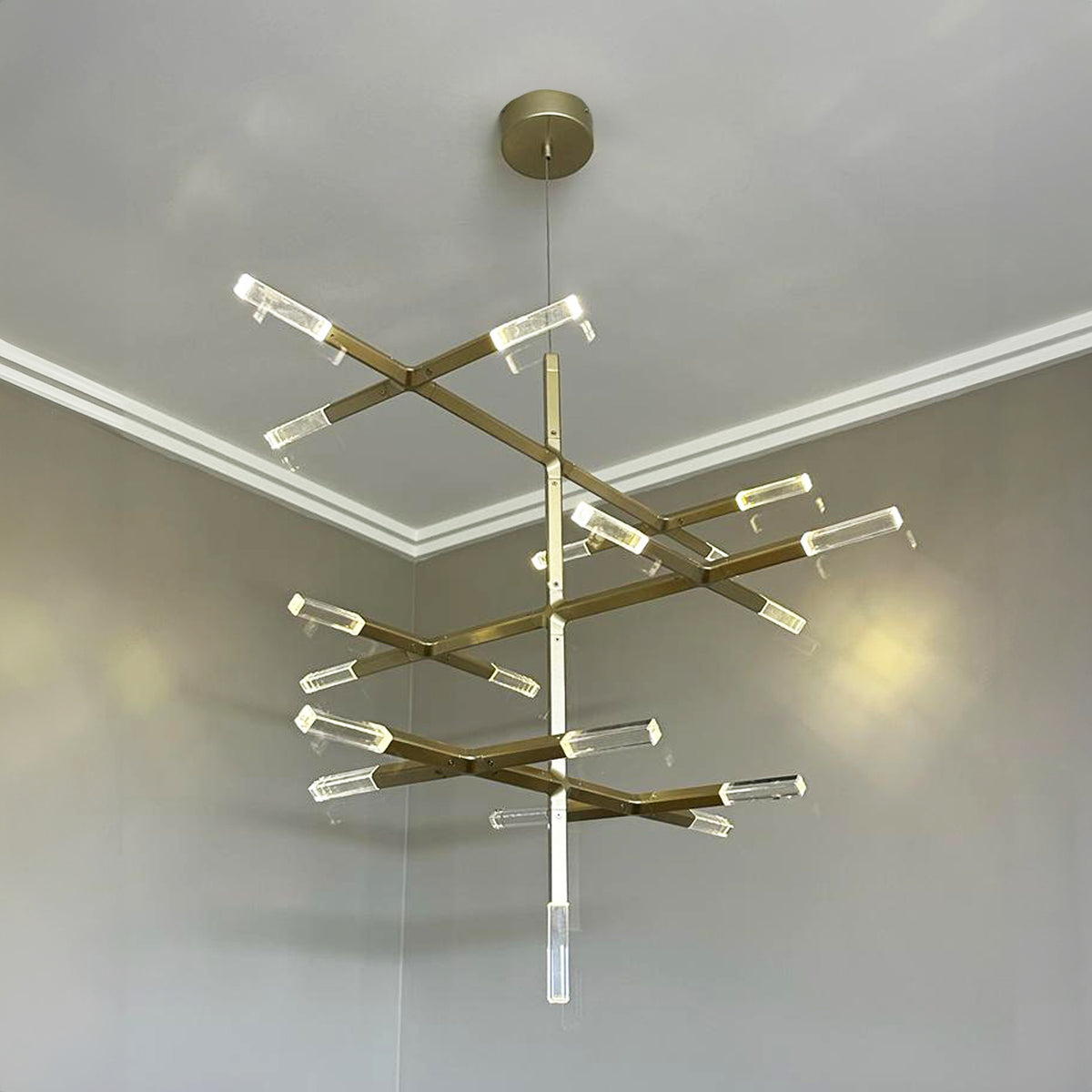 Modern chandelier with gold and clear design hanging from a ceiling.