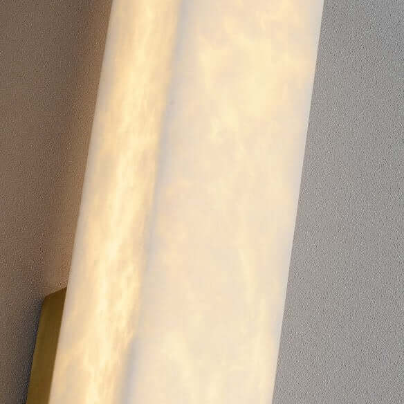 Wall-mounted light fixture with gold trim on a gray wall