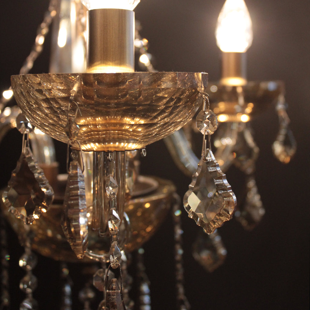 Close-up of a chandelier with amber toned crystal details on a dark background