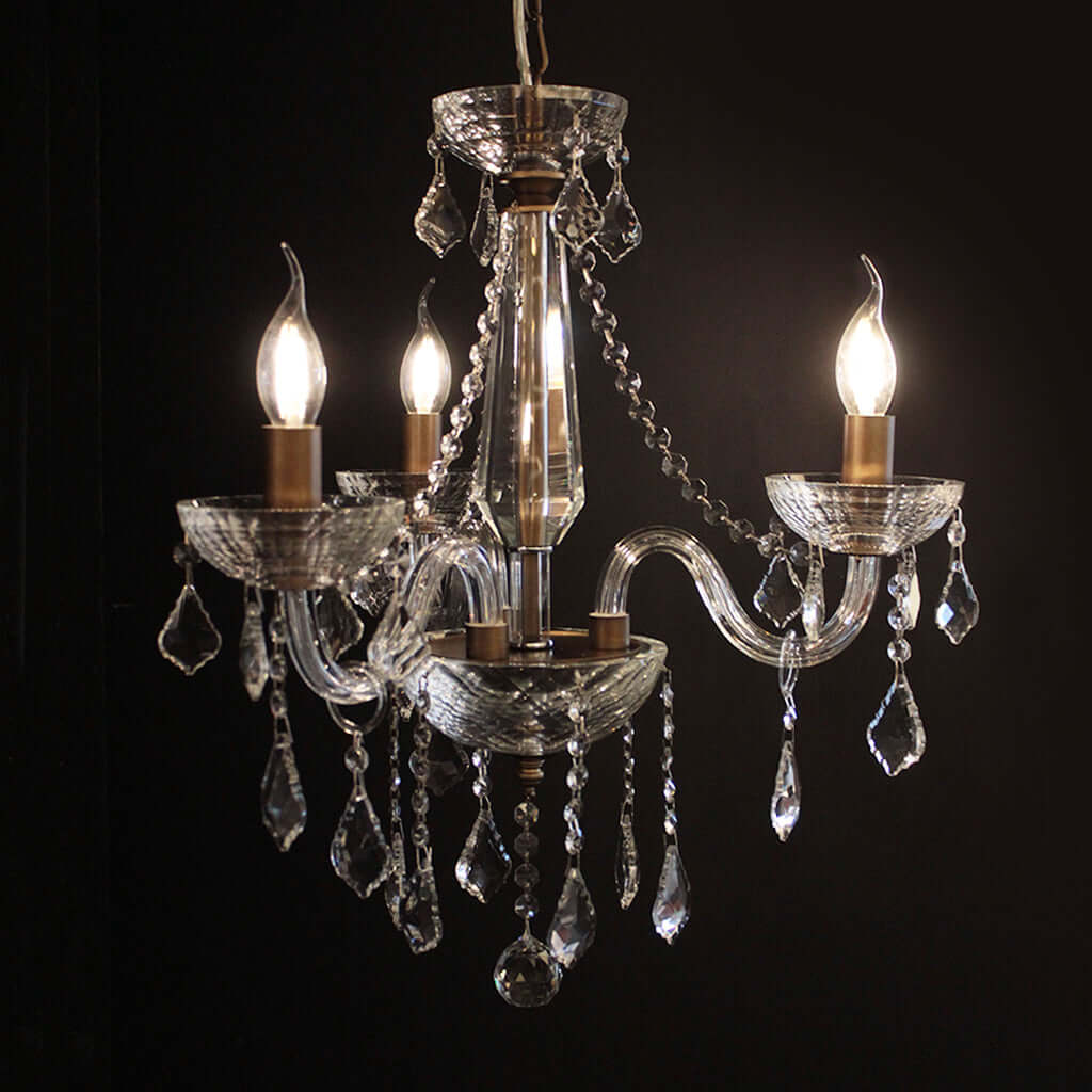 Crystal chandelier with three lit bulbs against a dark background