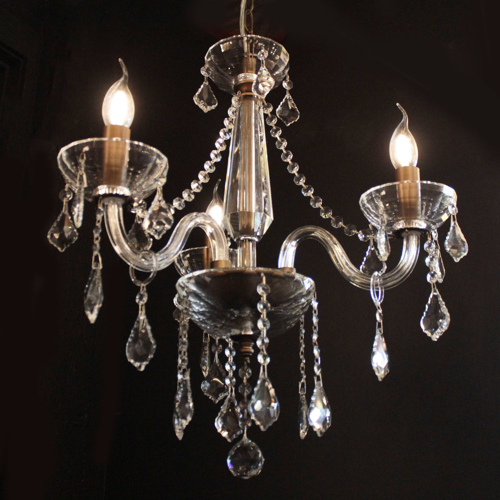 Crystal chandelier with three lit bulbs on a black background