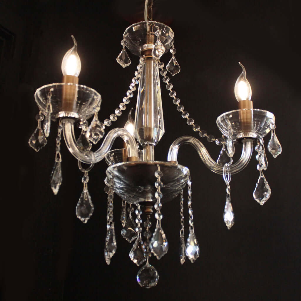 Crystal chandelier with three lit bulbs on a black background