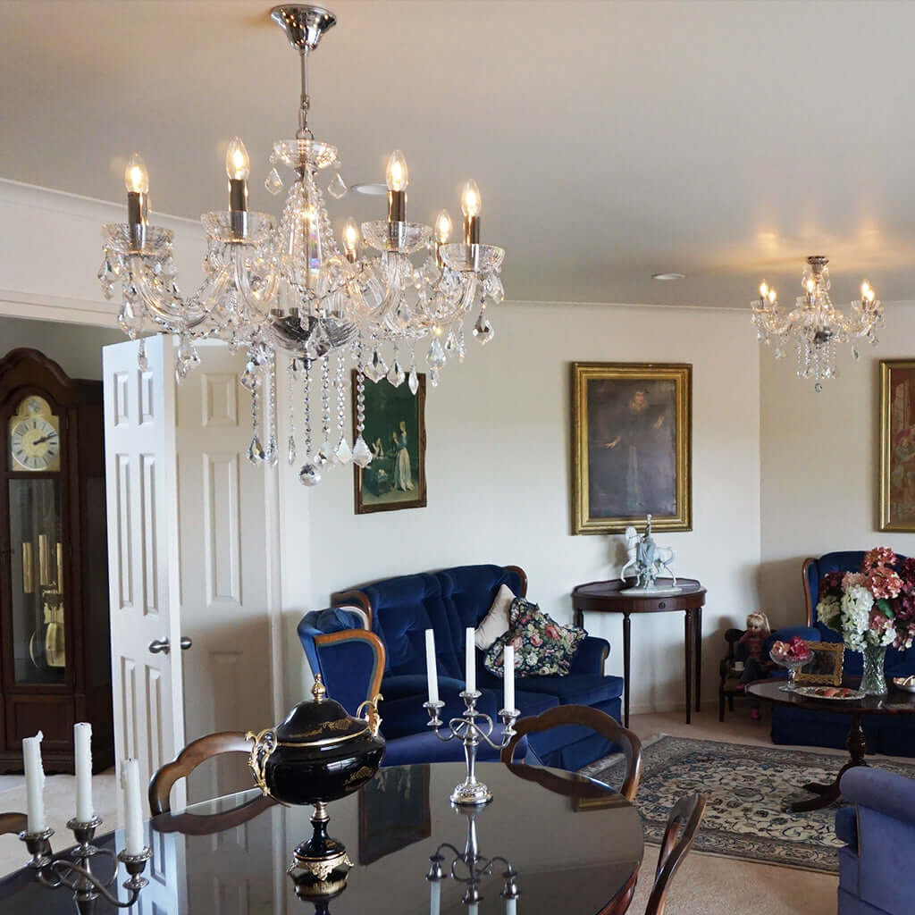 Living room with chandeliers, blue sofa, and decorative items.
