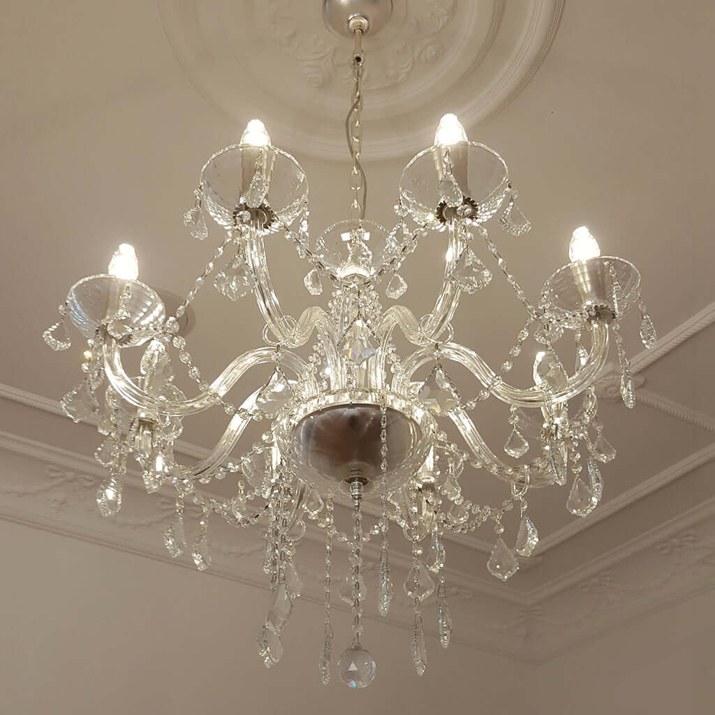 Crystal chandelier hanging from a ceiling with decorative molding.