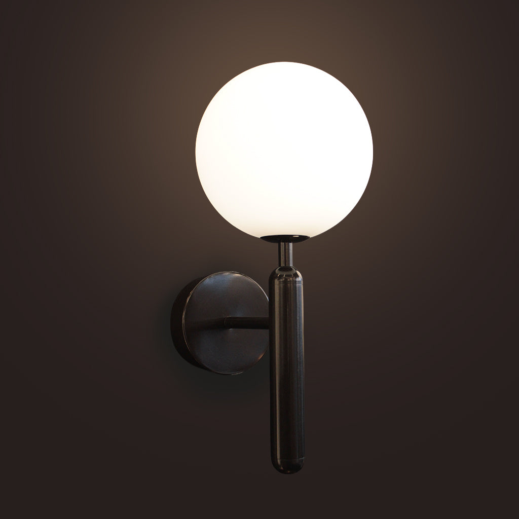 Wall-mounted light fixture with a round glass shade on a dark background