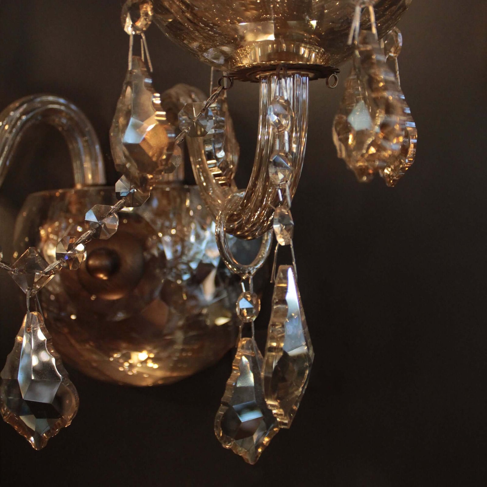 Crystal wall sconce with two light bulbs on a white wall.