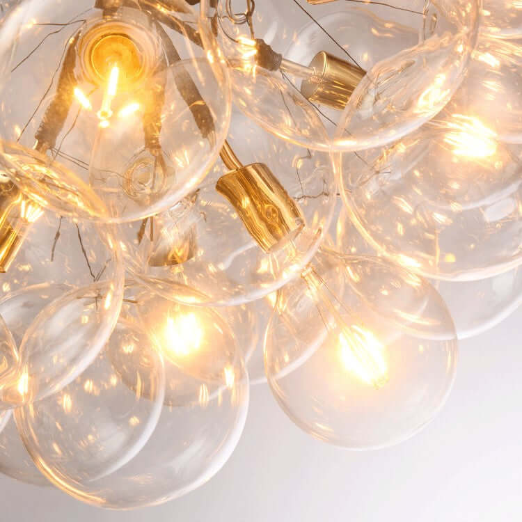 Close-up of a chandelier with clear glass bulbs and gold accents on a white background