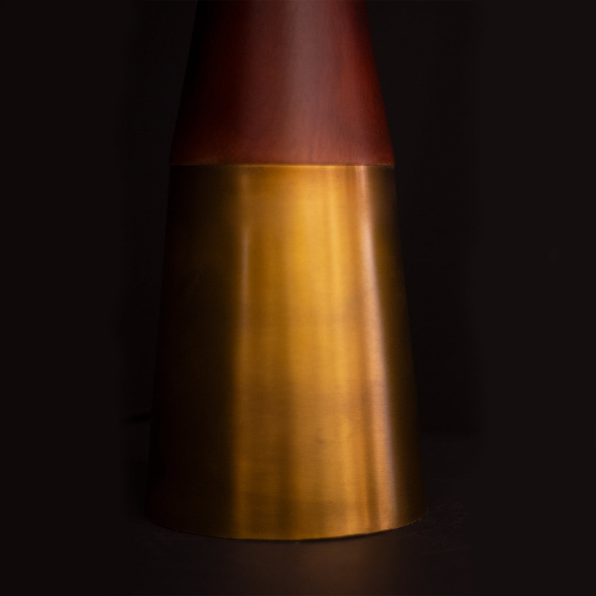 Decorative vase with a wood top and gold body on a dark background