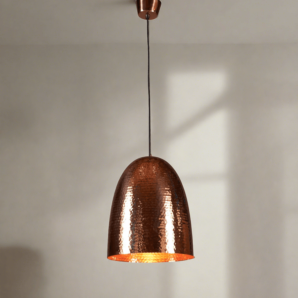 A tall domed pendant light with a hammered metal texture, constructed from a brass base, with a copper finish.