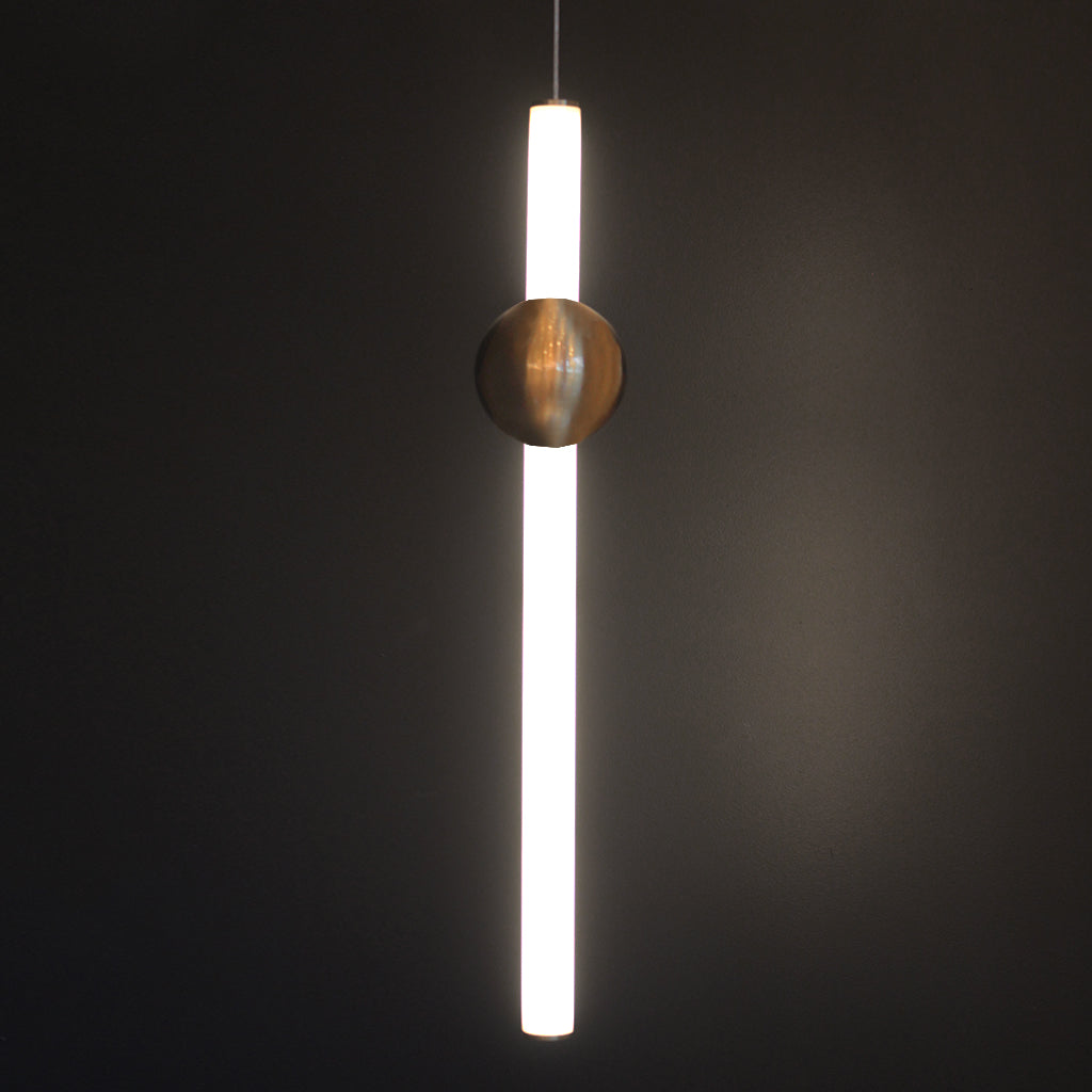 Modern pendant light with a cylindrical shade and spherical copper fixture on a dark background