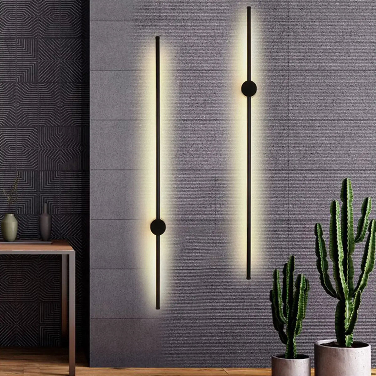 Contemporary wall lights with a matte black finish installed on a grey wall, with one light emitting a warm white glow.
