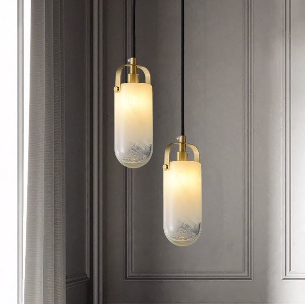 Two cylindrical Santina pendants with gradient textured glass shades and Brushed Brass detailing, hanging against a dark background.