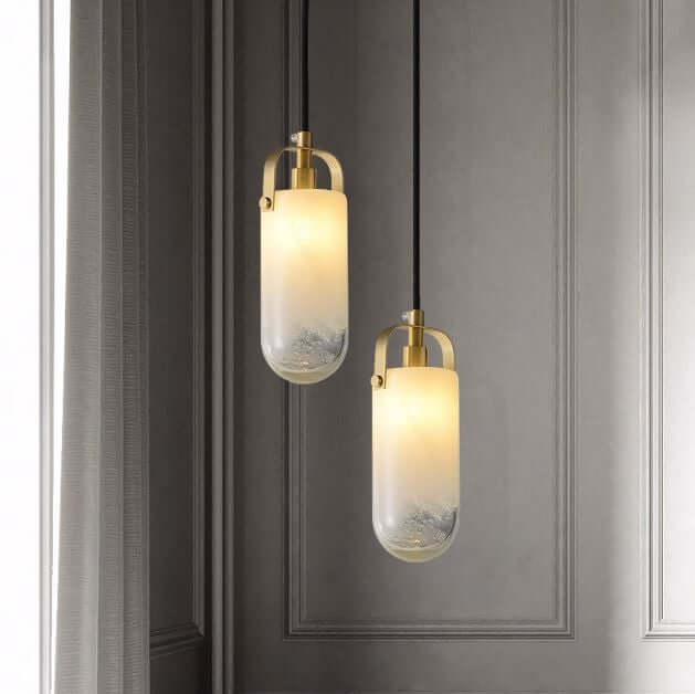 Two cylindrical Santina pendants with gradient textured glass shades and Brushed Brass detailing, hanging against a dark background.