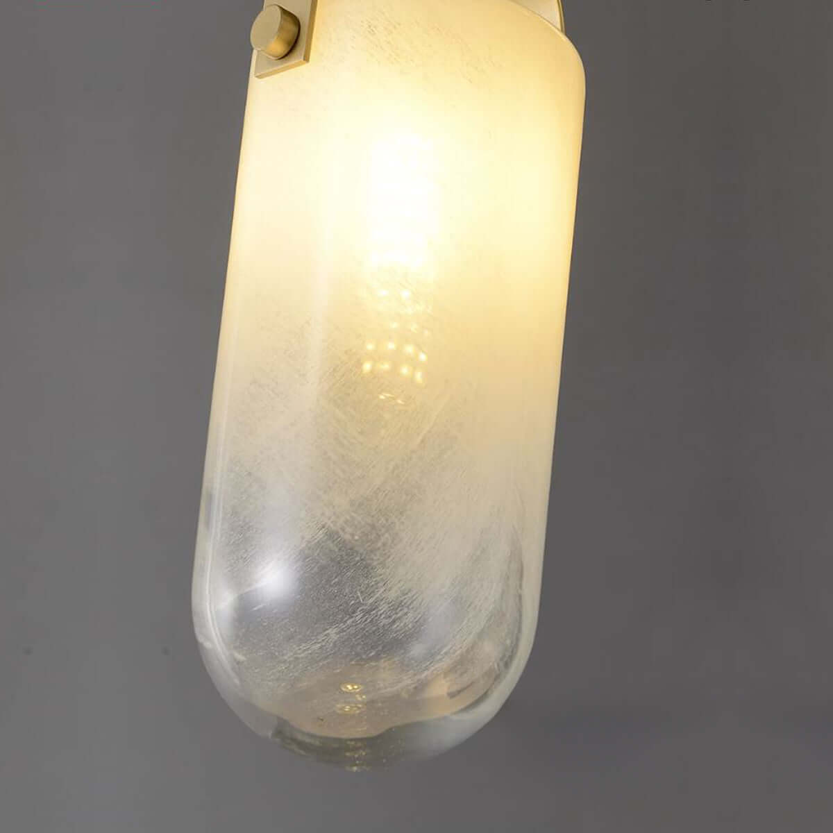 Two cylindrical Santina pendants with gradient textured glass shades and Brushed Brass detailing, hanging against a dark background.