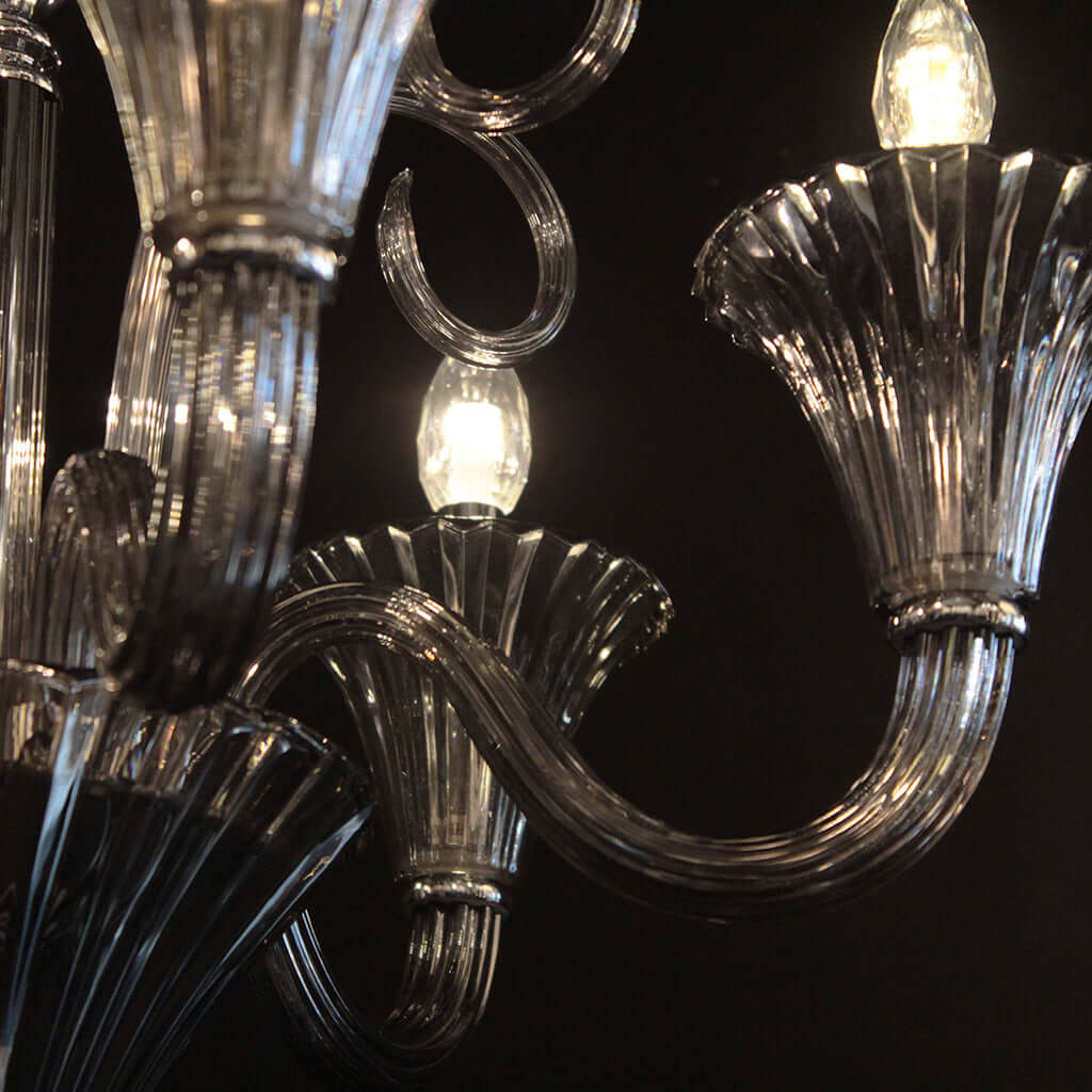 Close-up of a chandelier with smokey grey crystal and glass arms against a dark background