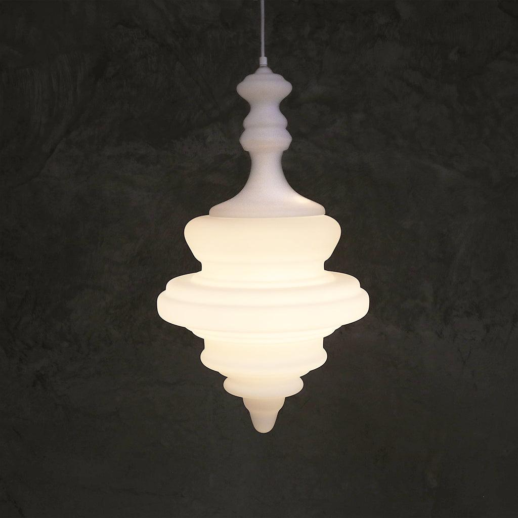 A white, sculptural pendant light with a tiered design hanging against a dark ground.