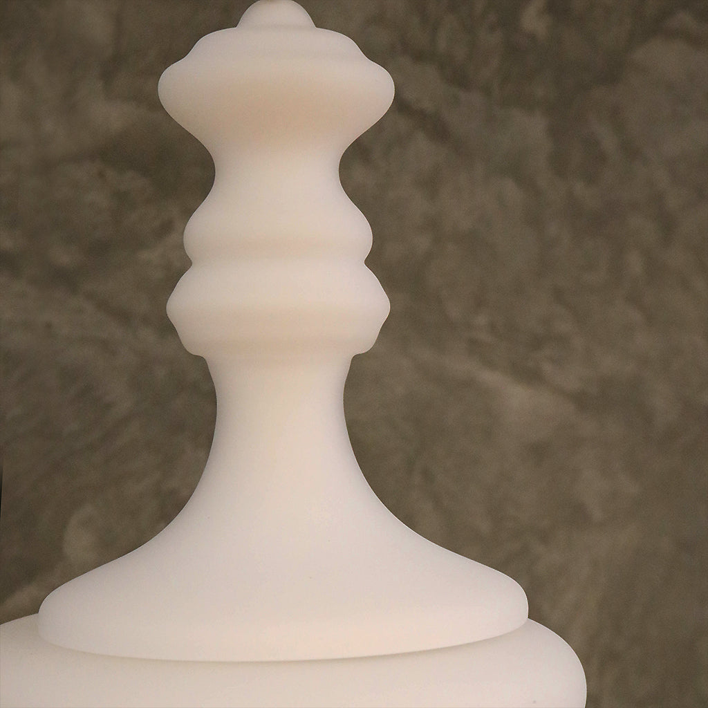 A white, sculptural pendant light with a tiered design hanging against a dark, textured background.
