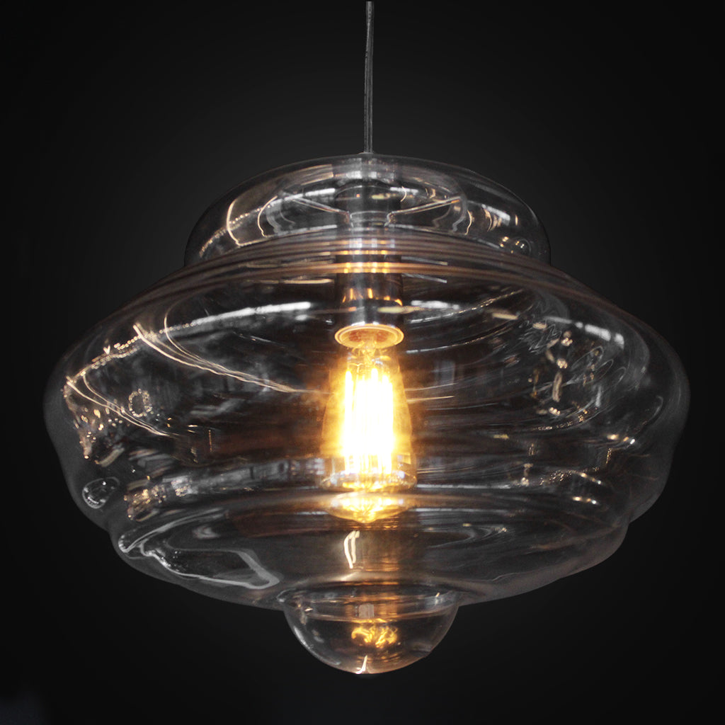 Clear glass pendant light with a visible bulb against a black background