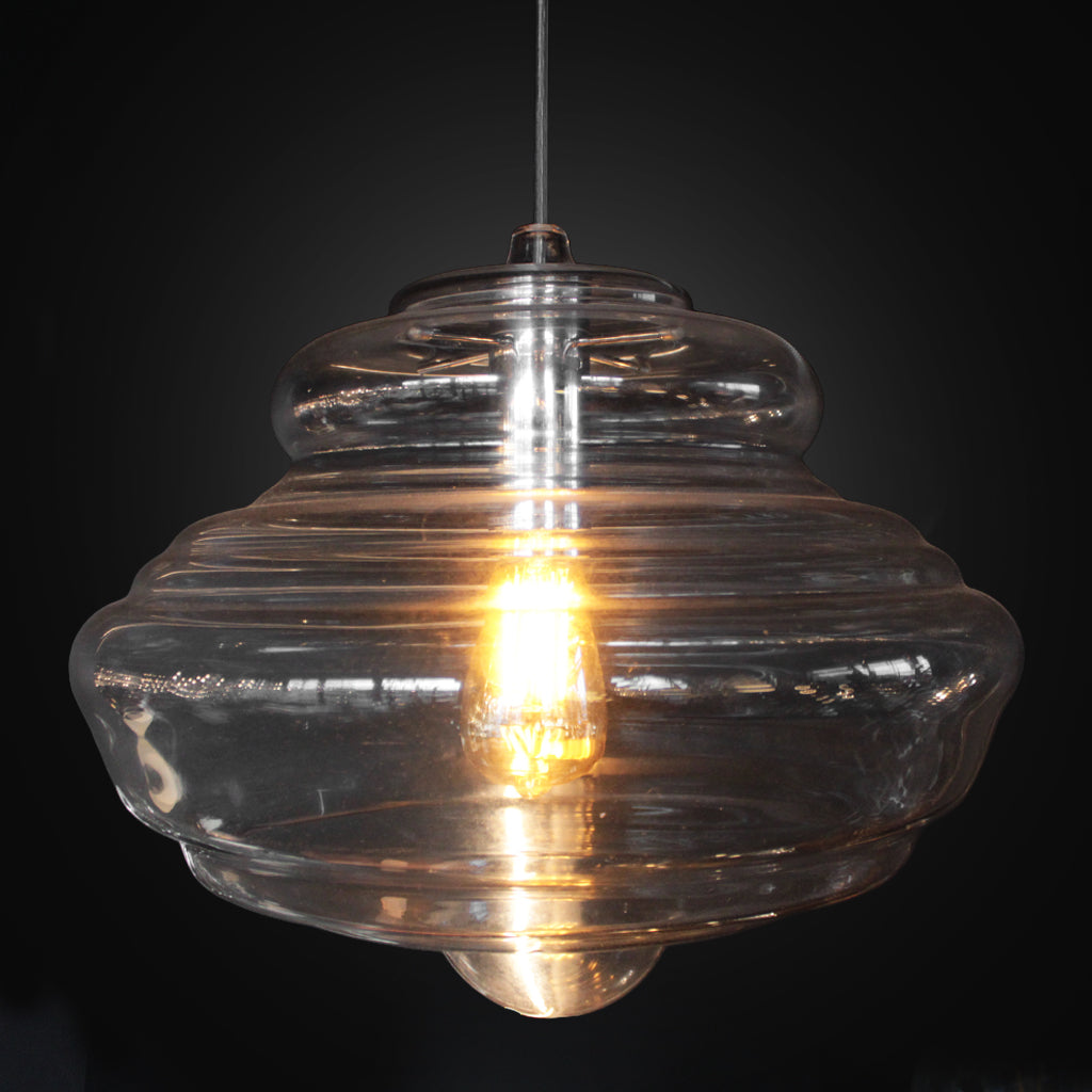 Clear glass pendant light with a visible bulb against a black background