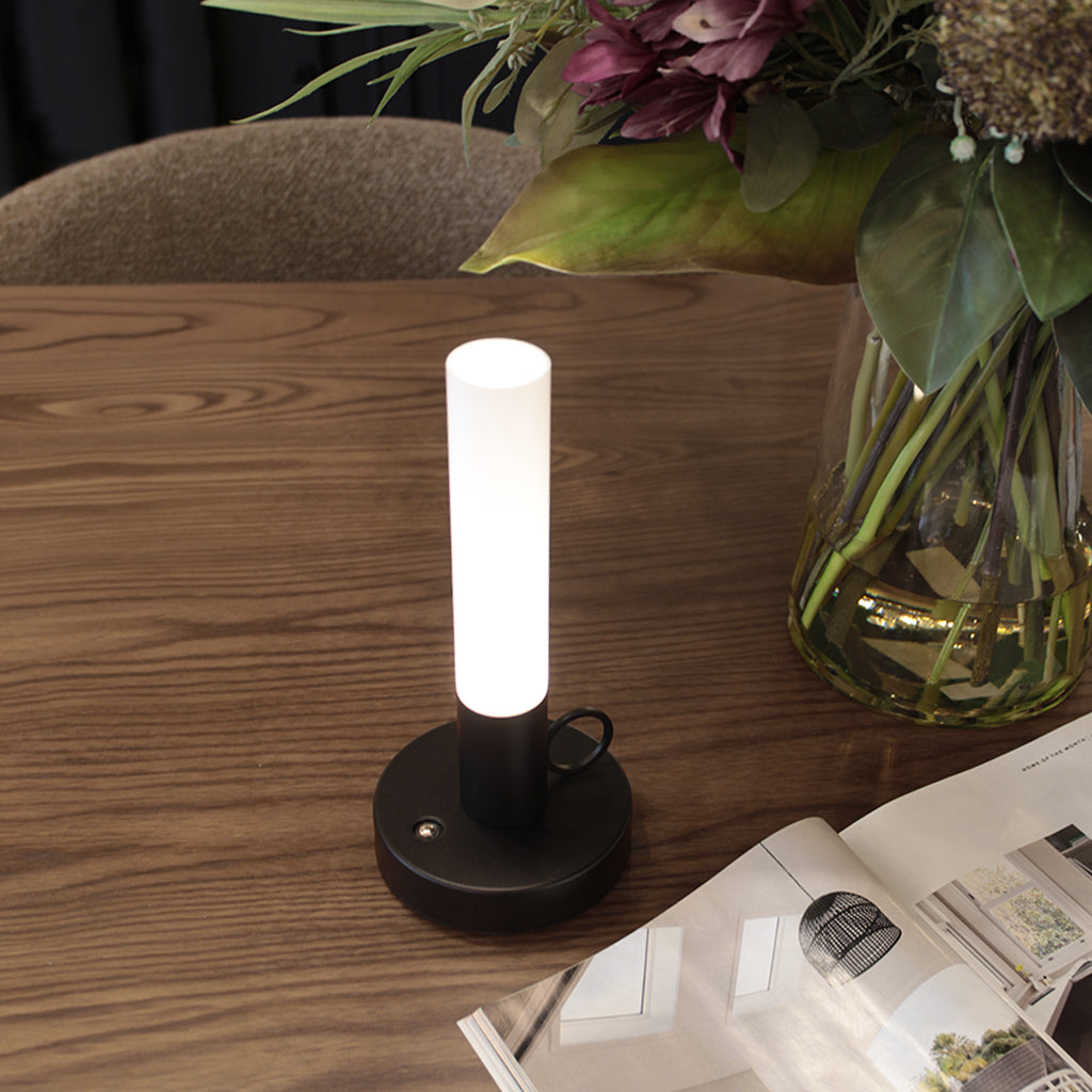 Black candlestick-style rechargeable portable LED table lamp on timber tabletop