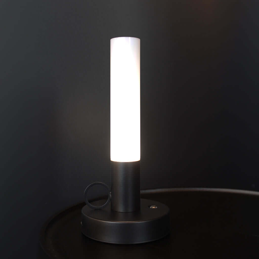 Black candlestick-style rechargeable portable LED table lamp on timber tabletop