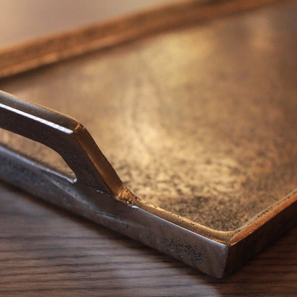 Close-up of a metallic tray with a handle on a wooden surface