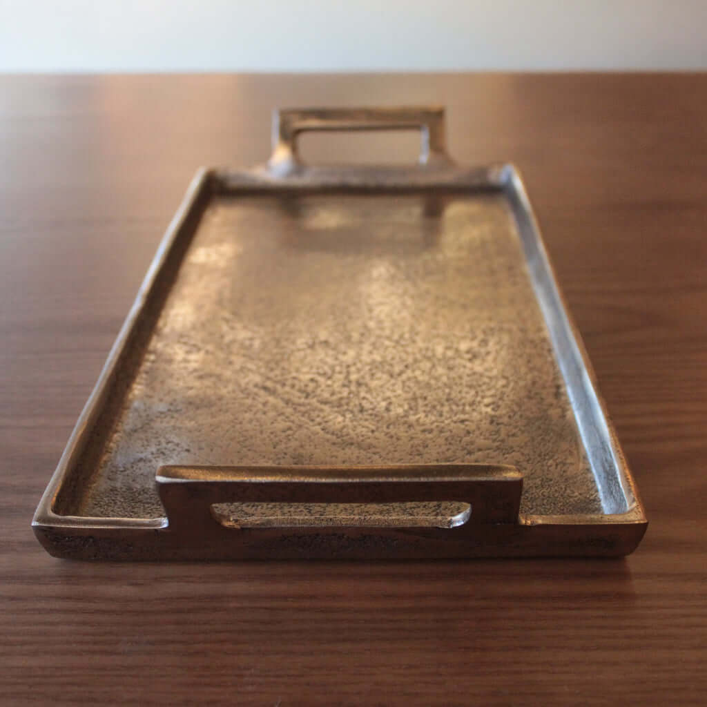 Bronze tray with handles on a wooden surface