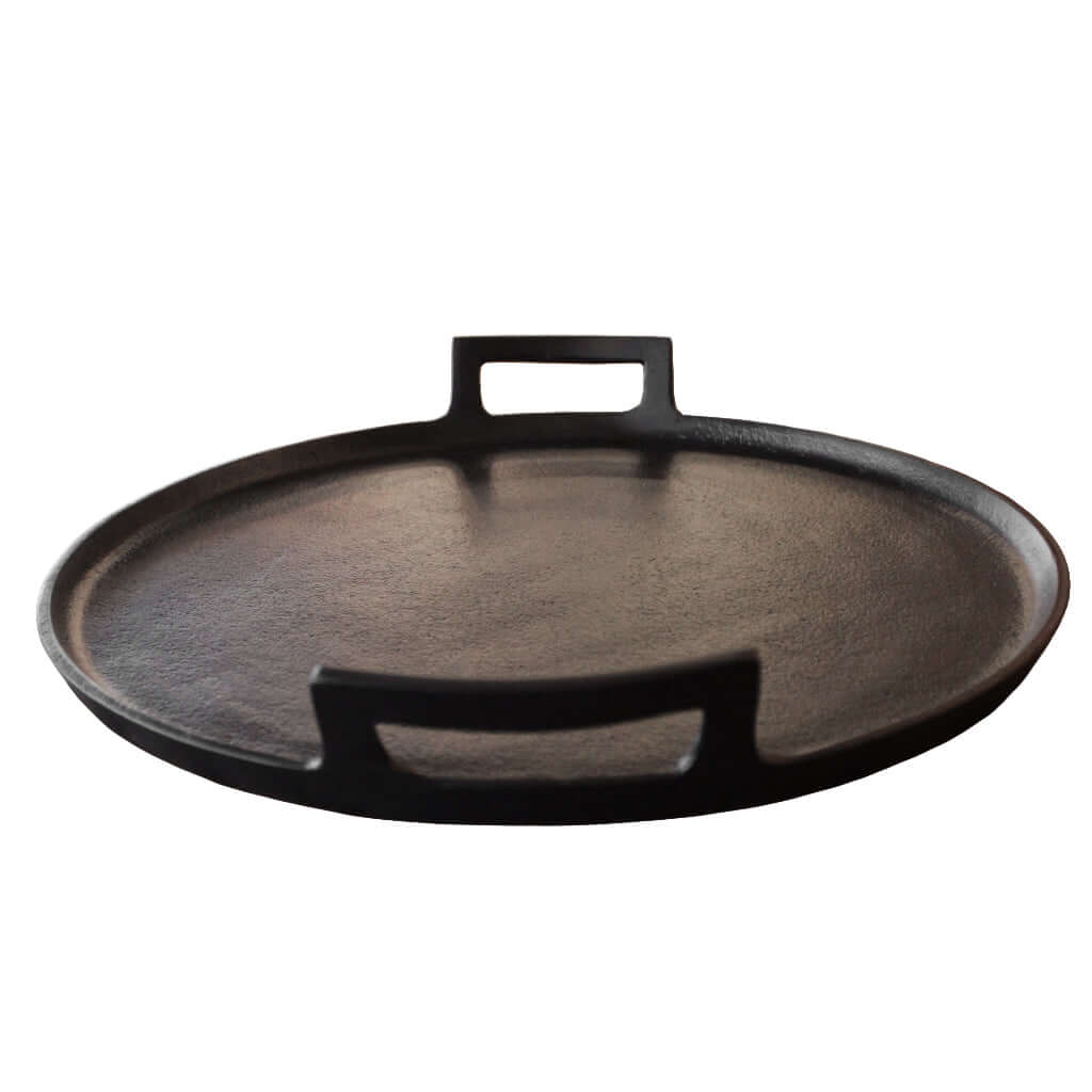 Black cast metal tray with handles on a white background