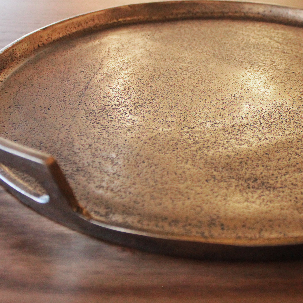 Close-up of a metallic tray with a reflective surface on a wooden surface.