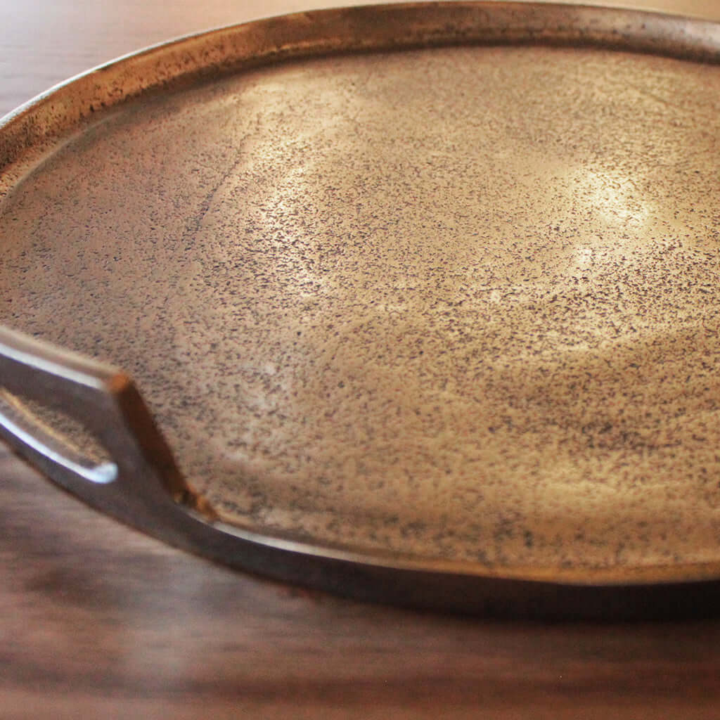 Close-up of a metallic tray with a reflective surface on a wooden surface.