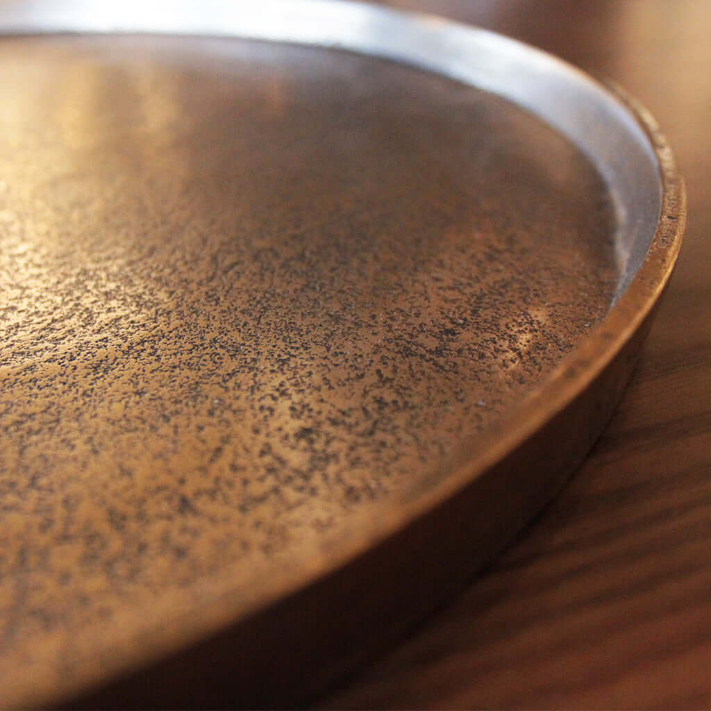 Close-up of a textured metal tray on a wooden surface