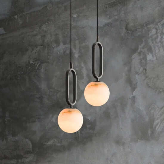 Two Zara pendant lights with a matt black frame and real Alabaster stone diffuser, hanging against a textured grey wall.