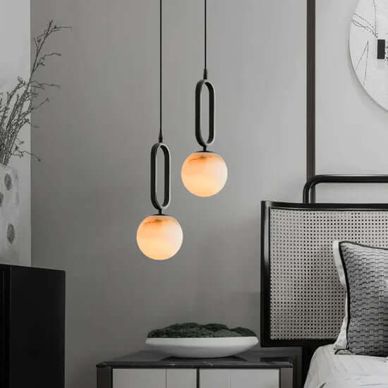 Two Zara pendant lights with a matt black frame and real Alabaster stone diffuser, hanging against a textured grey wall.
