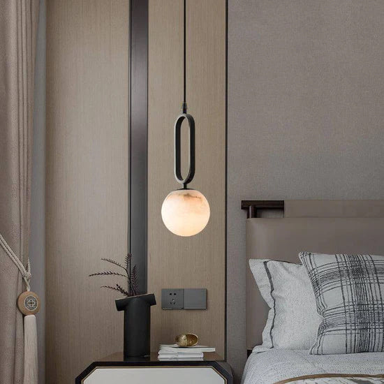 Alabaster and black pendant light next to bed