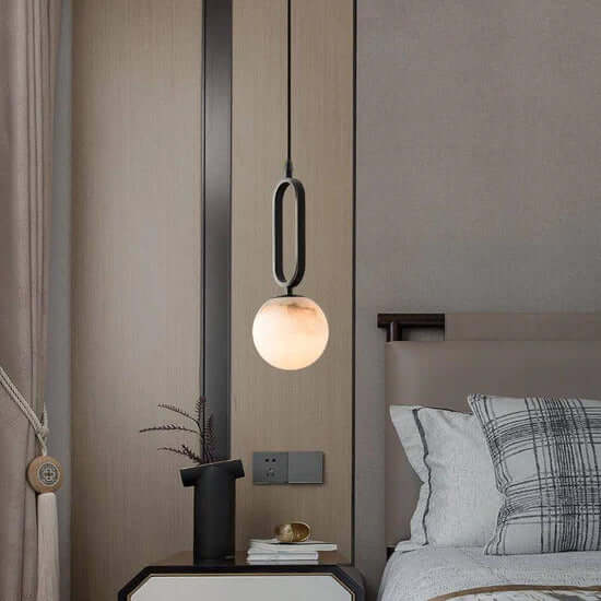 Alabaster and black pendant light next to bed