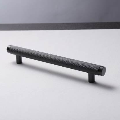 A black brass handle laid on a flat surface with a plain background.