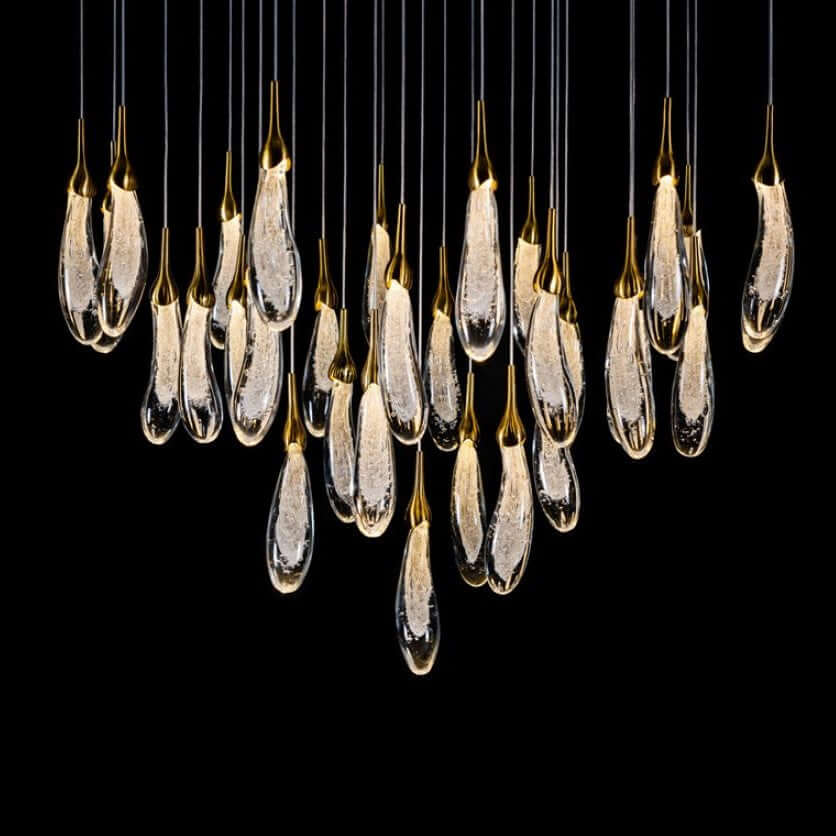 A hand-formed glass pendant light with a silver top, glowing from within, suspended from a cable.