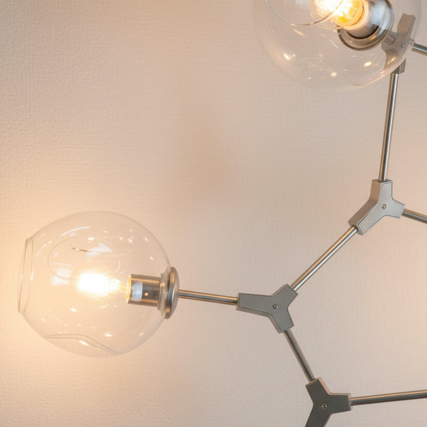 Modern chandelier hanging above a dining table with a neutral background