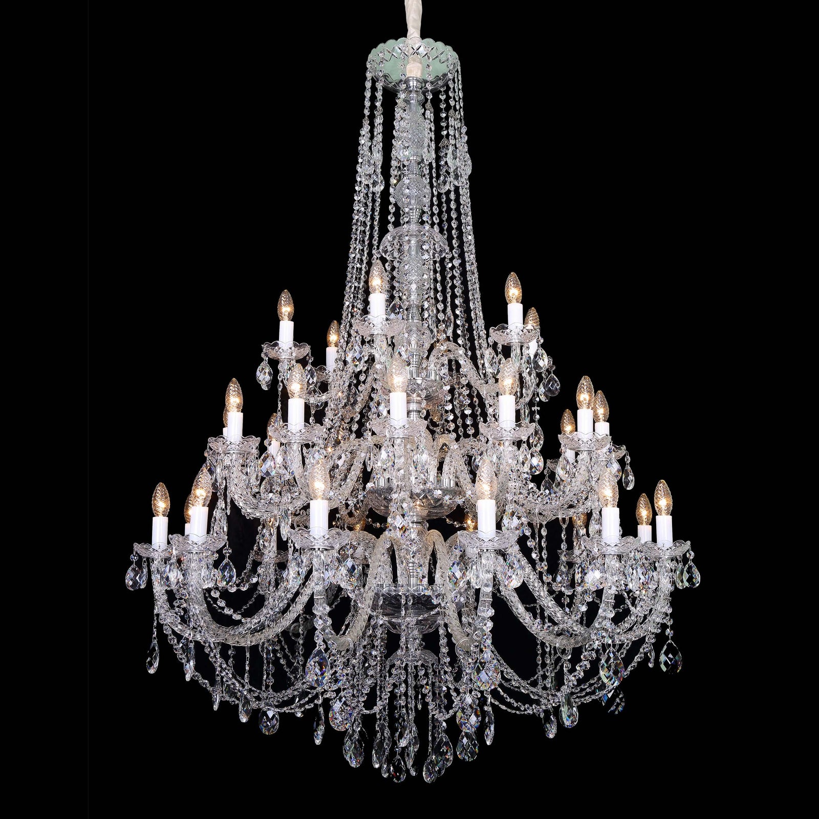 Crystal chandelier hanging in a room with a window and staircase.