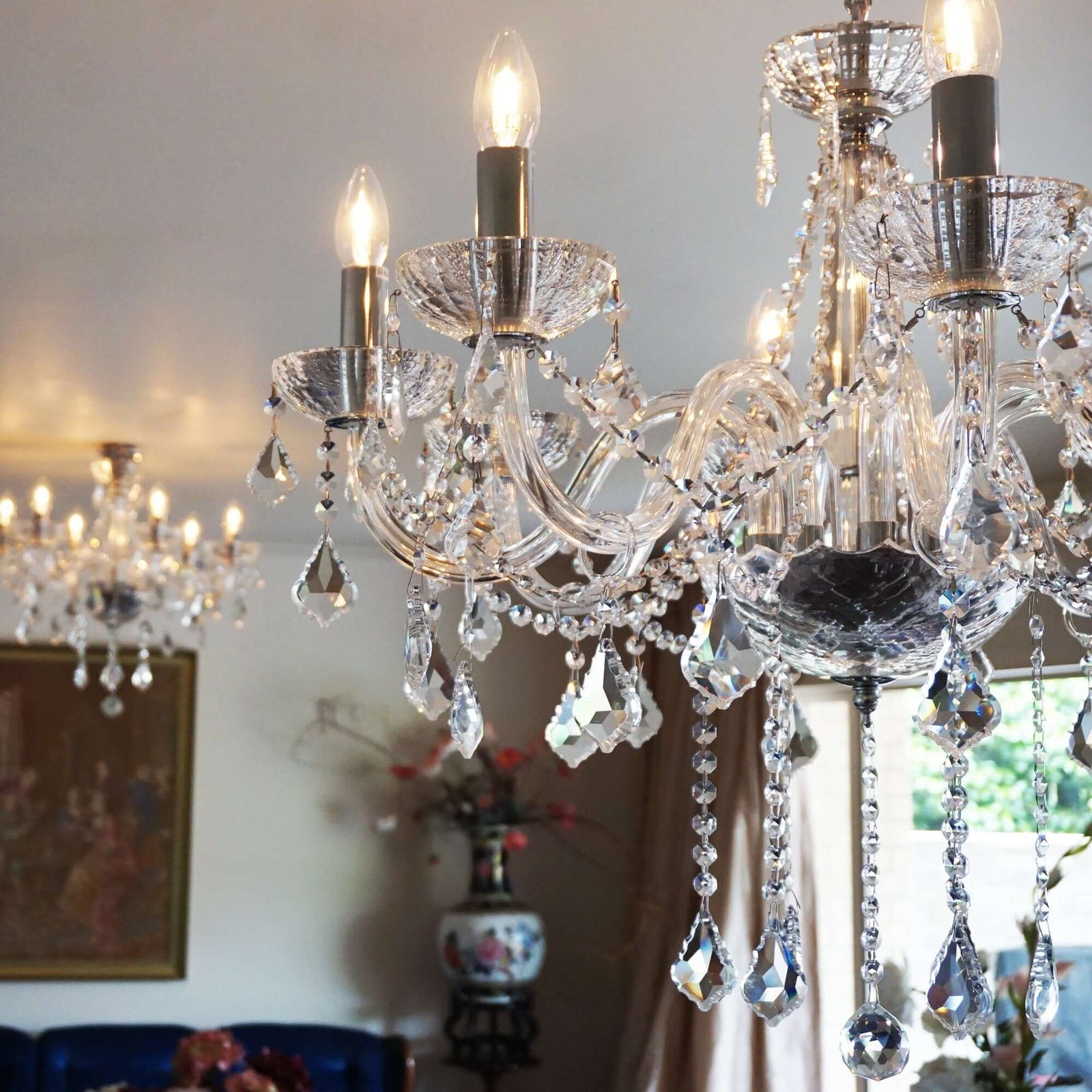 A clear crystal chandelier with faceted bowls and ribbed arms, with chrome silver accents, hanging in a room.