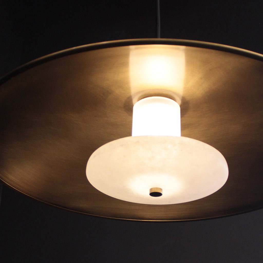 Close-up of a pendant light with a gold finish and white bulb on a dark background