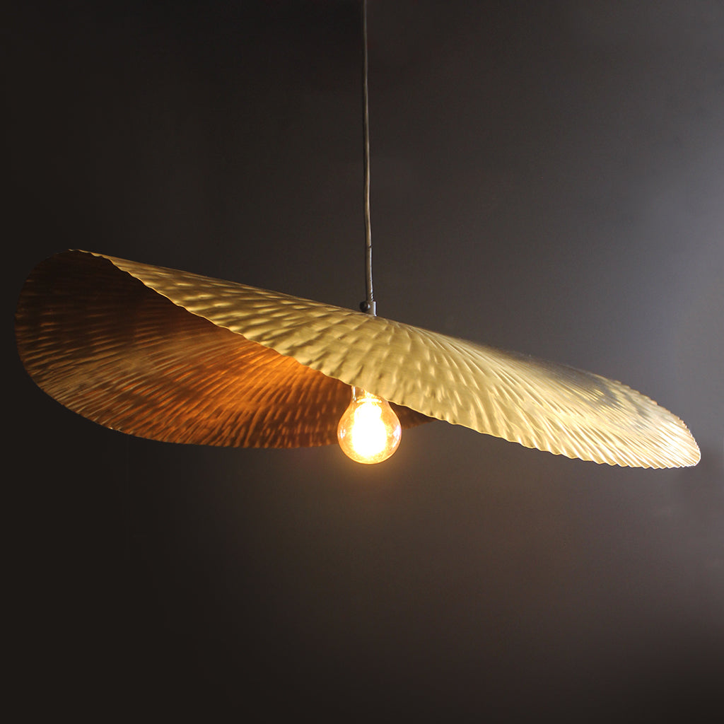 Gold leaf-like pendant light against a dark background