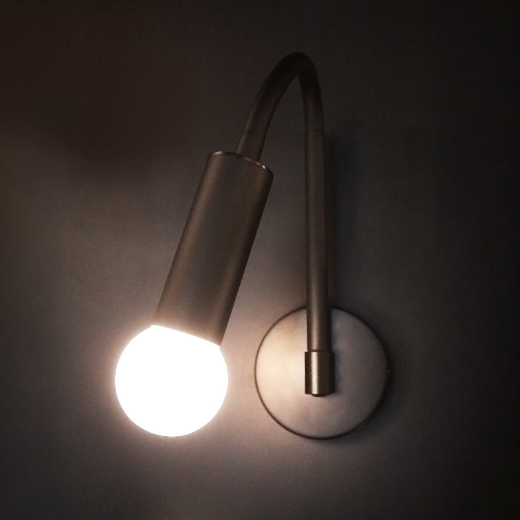 Modern wall light fixture with a single bulb on a dark background