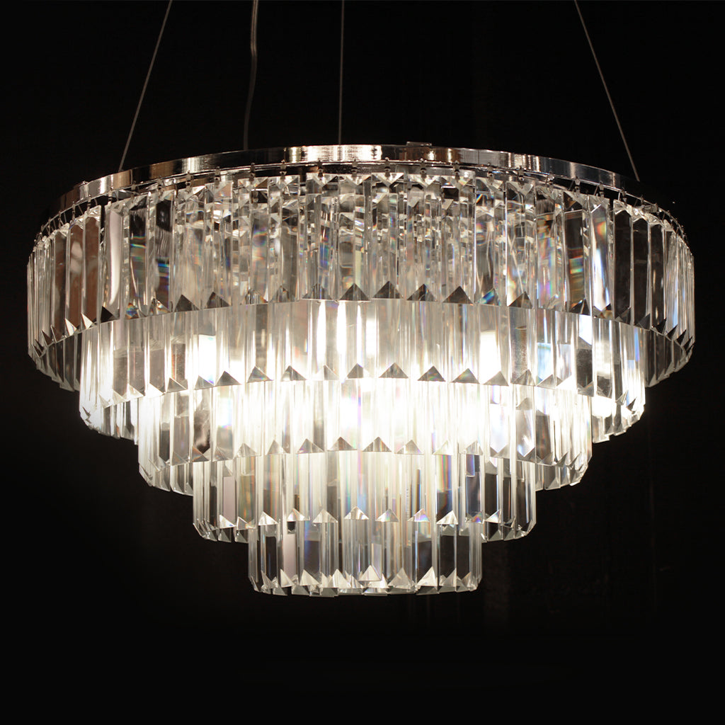 A tiered chandelier with clear prism crystals on a polished silver frame against a black background