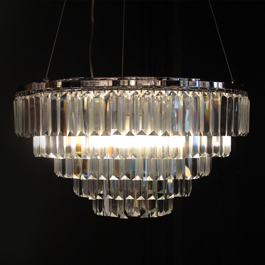 A tiered chandelier with clear prism crystals on a polished silver frame against a black background