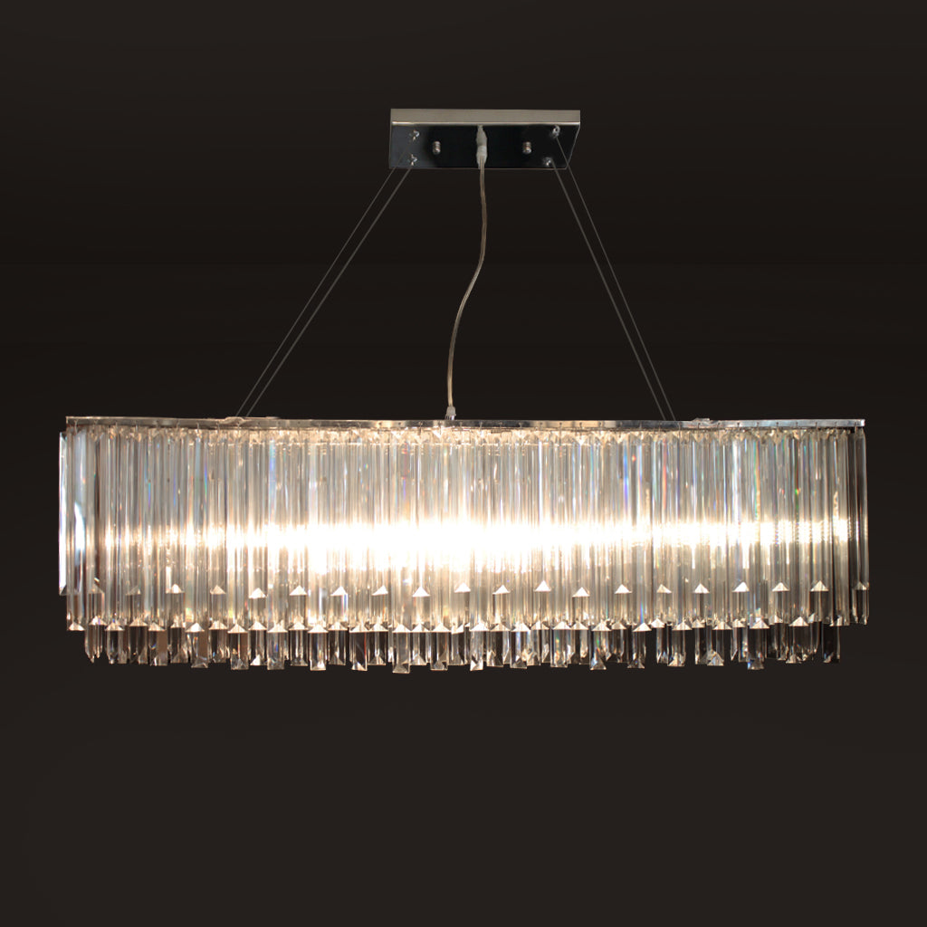 A modern rectangular chandelier with clear crystal vertical prisms, suspended from a rectangular ceiling mount against a dark background