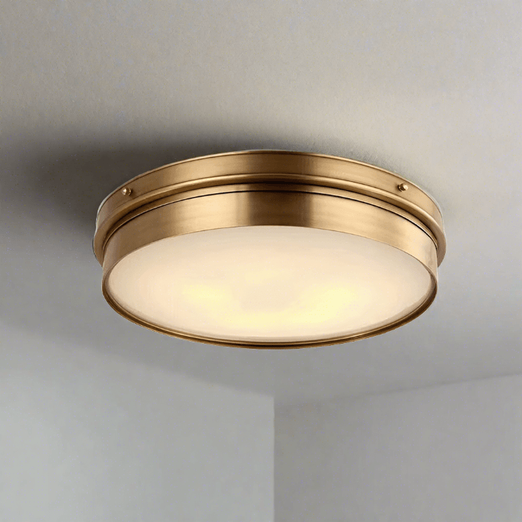 A round, brass ceiling-mounted light with a frosted glass cover, nautical-inspired design.