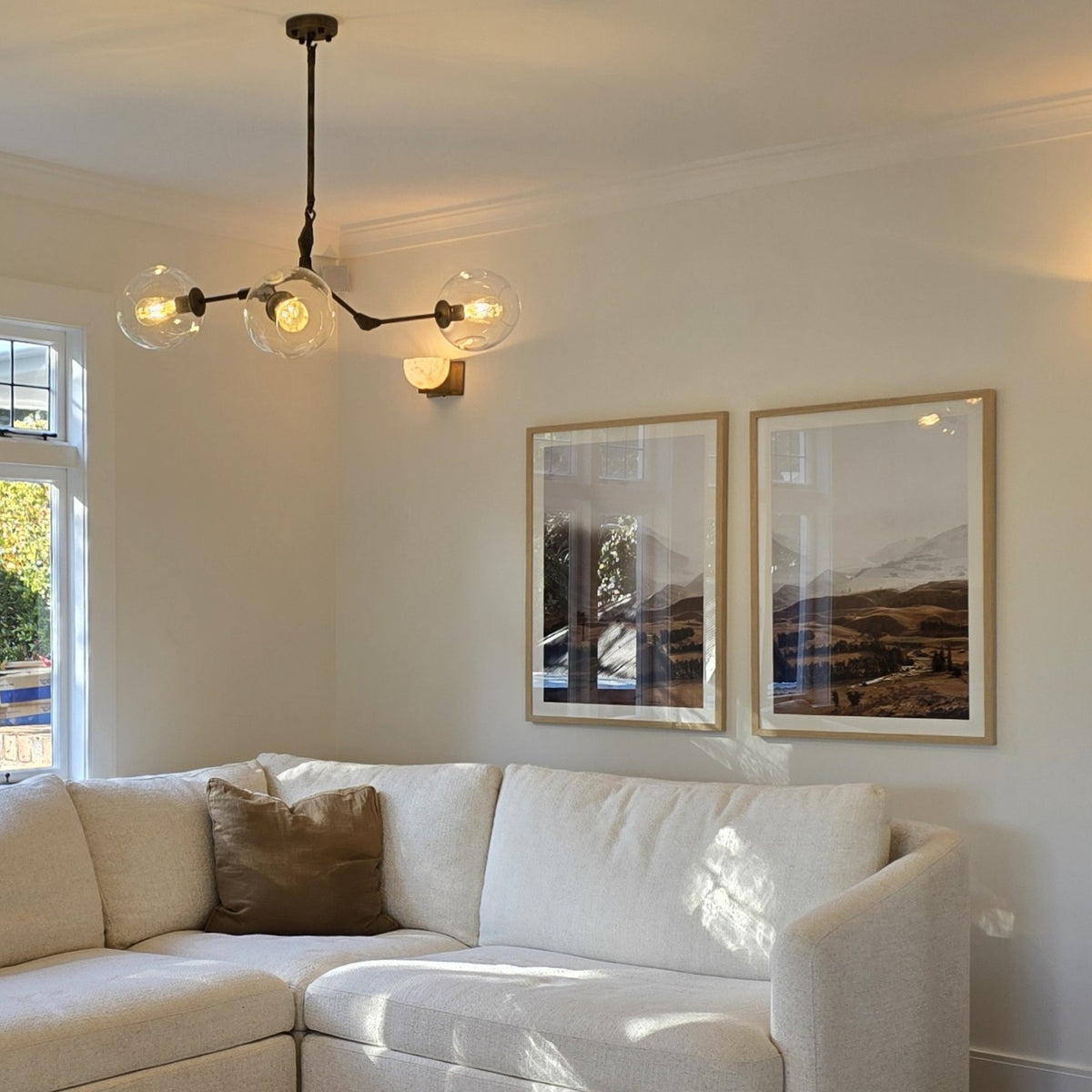 Living room with a white sofa, chandelier, and framed pictures on the wall.