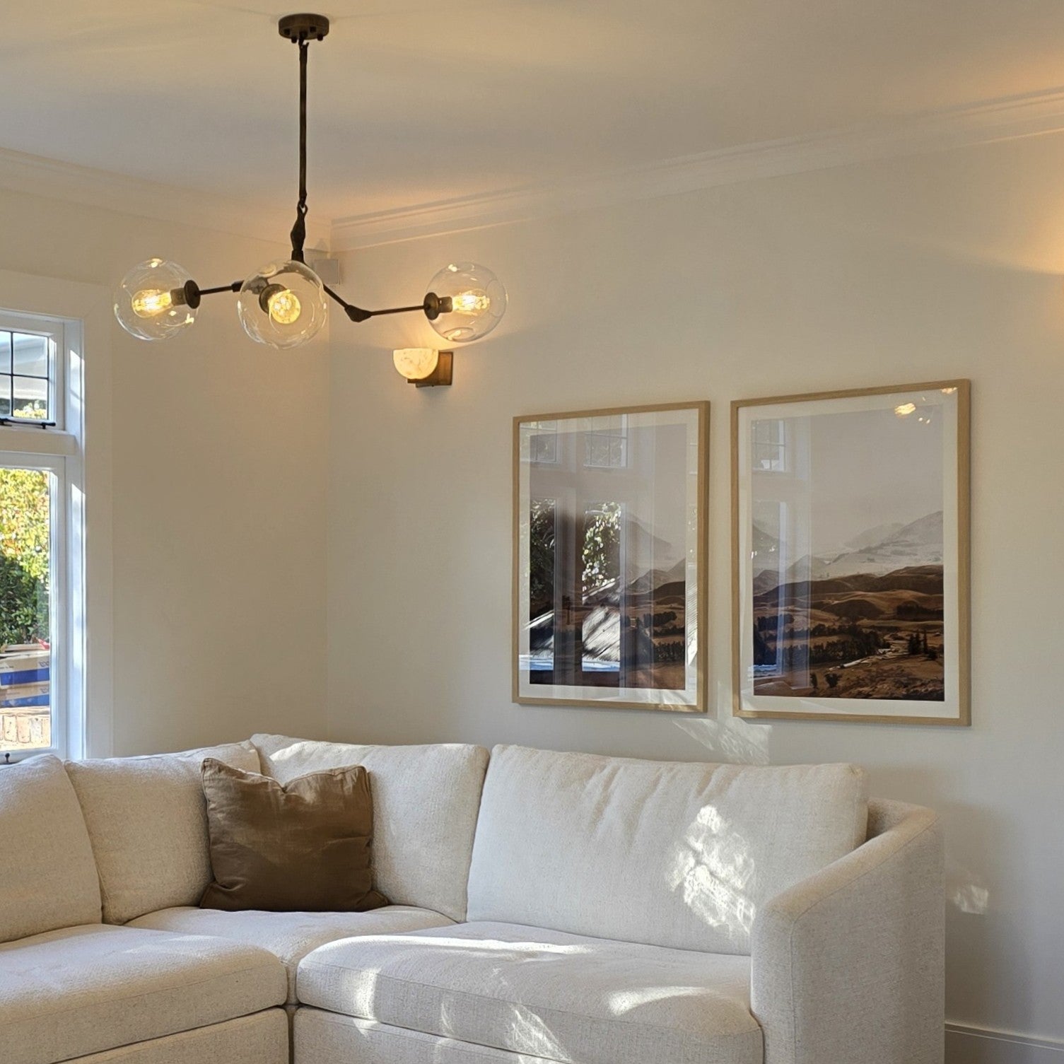 Living room with a white sofa, chandelier, and framed pictures on the wall.