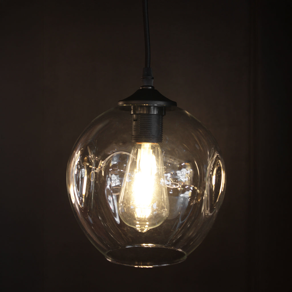 Clear glass pendant light with matt black fittings in front of dark background